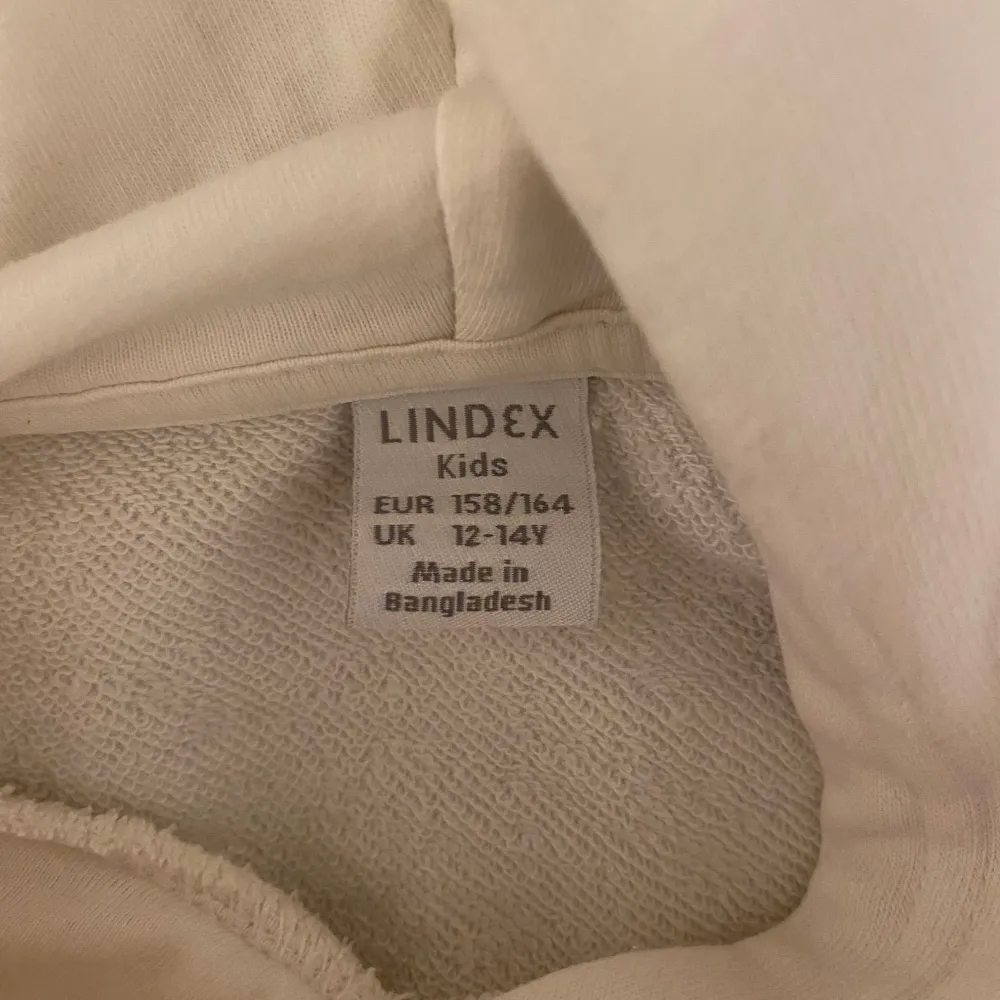 Säljer en stilren vit hoodie från Lindex i storlek 158/164. Den har en praktisk huva och dragsko i nederkanten för justerbar passform. Perfekt för en avslappnad look.. Neuletakit & Villapaidat.