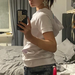 Vit kortärmad huvtröja - Säljer en vit kortärmad huvtröja med dragkedja framtill. Sitter avslappnat på mig som vanligtvis bär xs🫶