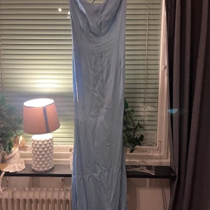 Ljusblå långklänning - Elegant ljusblå långklänning med en smickrande passform. Klänningen har en vacker drapering framtill och snörning i ryggen för en justerbar passform. Perfekt för speciella tillfällen. Den är använd en gång. 