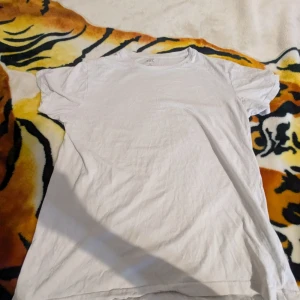 Vit t-shirt från Lager 157 - Säljer en klassisk vit t-shirt från Lager 157, modell Marlon. Den är tillverkad i 100% bomull och har en enkel design med korta ärmar. Perfekt basplagg för alla tillfällen.
