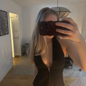 Svart topp med dragkedja - Snygg svart topp med dragkedja framtill och öppen rygg. 