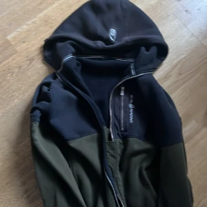 Svart och grön jacka med huva - Säljer en svart och grön jacka från Peak Performance. Jackan har en huva och dragkedja framtill. Perfekt för kyligare dagar med sin stilrena design och praktiska fickor.