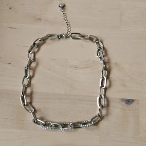 Silverfärgat halsband med länkar - Elegant halsband i silverfärg med stora länkar och dekorativa detaljer. Totala längd 42+8cm
