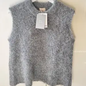 Säljer en mysig grå väst i ullblandning från H&M. Perfekt för lager-på-lager under kyliga dagar. Västen har en enkel design med rund hals och är ärmlös, vilket gör den lätt att matcha med olika outfits. Aldrig använd & prislappen finns kvar!