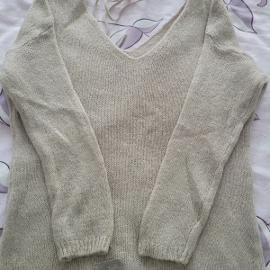 Beige stickad tröja med v-ringning - Säljer en mysig beige stickad tröja med v-ringning. Tröjan är tillverkad i Italien och består av 20% ull, 40% polyamid och 40% akryl. Perfekt för kyliga dagar.