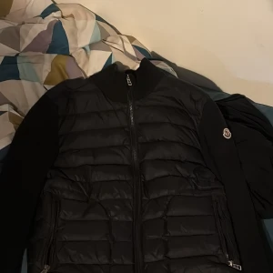 Moncler cardigan  - Snygg svart pufferjacka från Moncler med dragkedja. Jackan är i storlek M hör av er vid intresse. Bytan kan vara intressant eventuellt mot en annan cardigan.