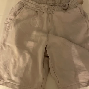 Ljus lilla shorts med resårmidja - Säljer ett par bekväma ljus lilla shorts med resårmidja och sidfickor. Perfekta för en avslappnad stil.