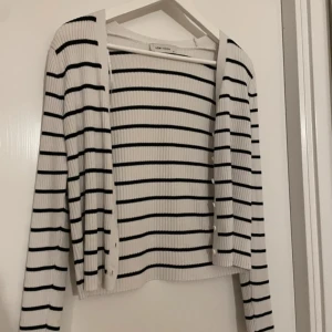 Vit och svart randig kofta från Love Stories - Säljer en stilren vit och svart randig kofta från Love Stories. Koftan är ribbad och har långa ärmar, perfekt för en avslappnad look. Den är öppen framtill och passar bra till både jeans och kjol.