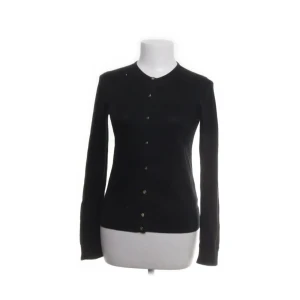 Svart kofta från Ralph Lauren - Snygg svart kofta från Ralph Lauren i 100% bomull. Den har långa ärmar och knappar framtill. Perfekt för en stilren look.