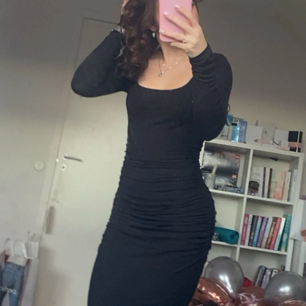 Snygg svart långklänning med tight passform och långa ärmar. Perfekt för en elegant look. Klänningen har en stilren design som framhäver figuren.. Mekot.