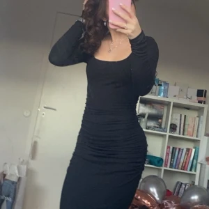 Svart långklänning - Snygg svart långklänning med tight passform och långa ärmar. Perfekt för en elegant look. Klänningen har en stilren design som framhäver figuren.