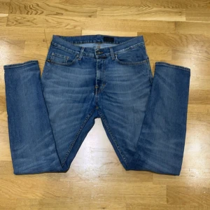 Blå jeans från Tiger of Sweden - Snygga blå jeans från Tiger of Sweden med klassisk femficksdesign och zipgylf. Jeansen har en rak passform och är perfekta för en stilren look. Tillverkade i slitstarkt denim med en lätt tvättad effekt. Pris kan diskuteras vid snabb affär