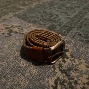 Beige bälte från Jack & Jones - Snyggt beige bälte från Jack & Jones med en robust silverfärgad spänne. Bältet har bruna skinn-detaljer som ger en stilren look.               Storlek, 90cm