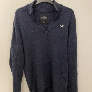 Mörkblå tröja med dragkedja från Hollister - Säljer en snygg mörkblå tröja från Hollister med dragkedja vid halsen. Tröjan har långa ärmar och en liten logga på bröstet. Perfekt för en stilren look. Skriv om du har funderingar och priset är inte hugget i sten!