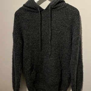 Grå stickad hoodie från NA-KD - Mysig grå stickad hoodie från NA-KD med en stor huva och dragsko. Perfekt för kyliga dagar med sin ribbade struktur och praktiska magficka. En stilren och bekväm tröja för alla tillfällen.