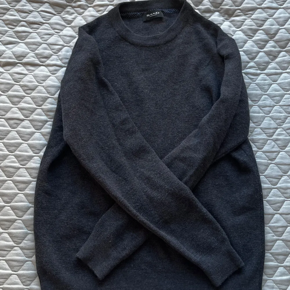 Säljer en stilren mörkgrå tröja från Sand Copenhagen i 100% merinoull. Tröjan har en klassisk design med rund hals och långa ärmar, perfekt för kyligare dagar. Ett måste för garderoben! 🖤den är i mycket gott skick och innehar samma fantastiska kvalitet som alla varor från Sand. Hör gärna av vid frågor, funderingar eller prisförslag:). Neuletakit & Villapaidat.