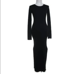 Svart långklänning från H&M - Elegant svart långklänning från H&M med långärmad design. Perfekt för en stilren och sofistikerad look. Klänningen har en figurnära passform som framhäver silhuetten. Den har dessutom slits på båda sidor.