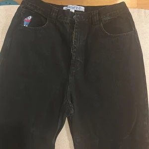Svarta jeansbyxor från Big Boy - Coola svarta jeansbyxor från Big Boy med en unik broderad detalj på framsidan. Byxorna har en klassisk femficksdesign och en dragkedja framtill. Perfekta för en avslappnad stil. Passade mig inte då de var för baggy för mig, bara provade aldrig använda 