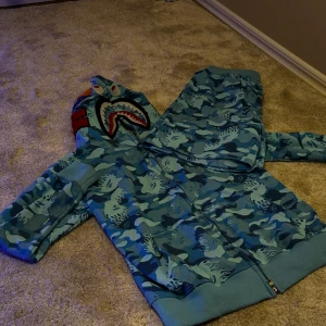 Blå Bape Camo Tröja + Shorts Set - Säljer en blå camo hoodie med matchande par shorts. Den har en dragkedja framtill och långa ärmar. Perfekt för dig som vill sticka ut med en unik stil för sommaren eller en sen vår. Aldrig använt (bara testat)