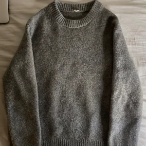 Grå stickad tröja från arket  - Säljer en mysig grå stickad tröja från Arket. Tröjan har en klassisk rund halsringning och långa ärmar. Perfekt för kyliga dagar. Passar bra till jeans. Storlek medium men sitter som xs 