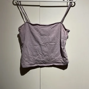 Ljuslila linnetopp - Säljer en söt ljuslila linnetopp med smala axelband. Perfekt för varma dagar och kan enkelt matchas med olika outfits. Toppen är enkel och stilren.