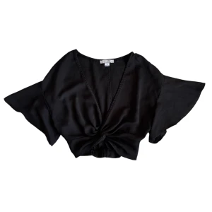 Svart omlott blus - Snygg svart omlott blus med korta vida ärmar och knytning framtill. Perfekt att styla över en spets-linne för en chic look!