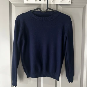 Mörkblå stickad tröja - Säljer en stilren mörkblå stickad tröja med rund halsringning. Tröjan har långa ärmar och ribbade muddar vid ärmslut och nederkant❣️