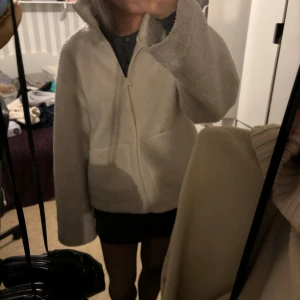 Beige teddyjacka med dragkedja - Mysig beige teddyjacka med dragkedja framtill. Perfekt för kyliga dagar med sin fluffiga och varma design. Jackan har långa ärmar och en hög krage för extra värme. En stilren och bekväm jacka för alla tillfällen💕