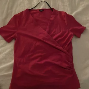 Rosa omlottopp från Ril's - Säljer en snygg rosa omlottopp från Ril's. Toppen har korta ärmar och en elegant omlottdesign som ger en stilren look. Perfekt för att piffa upp garderoben! Använd ändats 1 gång!❤️