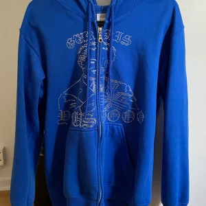 Blå hoodie med dragkedja - Säljer denna zip hoodie då den inte kommer till användning. Några paljetter har trillat av men man ser ändå trycket. Tröjan är i storlek s men passar även xs. Tveka inte för att höra av er vid frågor, pris går att sänkas! Ny pris 749 tror jag. SKRIV INNAN KÖP!!