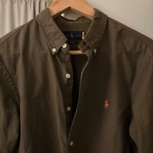 Olivgrön skjorta från Ralph Lauren - Säljer en snygg olivgrön skjorta från Ralph Lauren i slim fit. Skjortan har långa ärmar och klassiska knappar framtill. Perfekt för både vardag och fest! 🕺
