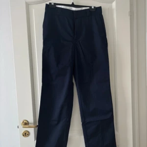 Mörkblå kostymbyxor - Säljer ett par mörkblå baggy kostymbyxor i mycket bra skick. De har en klassisk design med raka ben och hög midja, kan även bäras på två olika sätt! Endast använda en gång, därav mycket bra skick! Från H&M, passar storlek: S/M