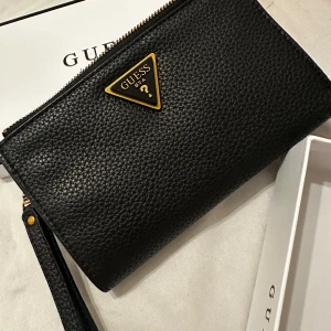 Svart plånbok från Guess -  svart plånbok från Guess i skinn. Den har en praktisk dragkedja och flera fack för kort och kontanter. Perfekt för både vardag och fest! 🖤köpt på zalando men aldrig använt. 