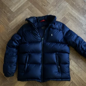 Mörkblå vinterjacka Polo Ralph Lauren - Säljer en snygg mörkblå pufferjacka från Polo Ralph Lauren i barn storlek XL vilket motsvarar XS/S. Den är i mycket bra skick. Det är performance modellen
