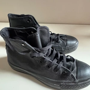 Svarta Converse All Star i skinn - Helt nya! Säljer ett par svarta Converse All Star i skinn. De har klassisk snörning och är i bra skick. Perfekta för både vardag och fest! Storlek dam 35.