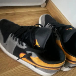 Nike Air Jordans i svart och orange - Säljer ett par Nike Air Jordans i svart och orange. Skorna har en snygg design med grå detaljer och klassisk snörning. Perfekta för både vardag och fest. De är i bra skick och redo för nya äventyr! Pris kan diskuteras.