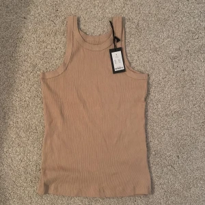Beige ribbad linnetopp - Säljer en snygg beige ribbad linnetopp i nytt skick. Perfekt som ett basplagg i garderoben. Toppen har en enkel och stilren design med breda axelband🧡🍂
