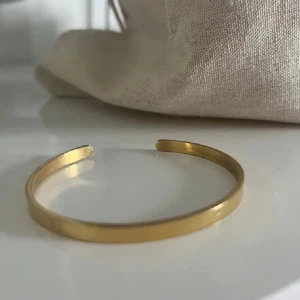 Guldarmband i minimalistisk stil - Snyggt och enkelt guldarmband i minimalistisk design. Perfekt för både vardag och fest. Armbandet har en slät yta och är lätt att matcha med andra smycken. Ett måste för den stilmedvetna!