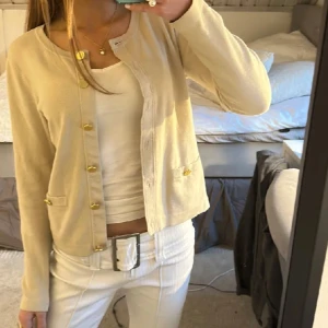 Beige kofta Stockh LM - Säljer en superfin beige kofta från Stockh LM. Den har långa ärmar och snygga guldknappar framtill. Perfekt för både vardag och lite finare tillfällen. Koftan är i mycket fint skick!