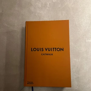 Louis Vuitton Catwalk - Säljer min bok från Thames & Hudson. Boken heter 'Louis Vuitton Catwalk' och är fylld med fantastiska modebilder och designer från Louis Vuitton. Perfekt för modeälskare och de som vill ha inspiration från catwalken. Boken har ett stilrent och elegant utseende med svart text på framsidan.