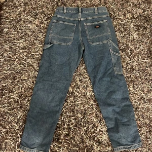 Blå jeansbyxor från Dickies - Säljer ett par baggy blå jeansbyxor från Dickies med praktiska fickor.  Byxorna är i mycket bra skick. Storlek L och 30 i längd