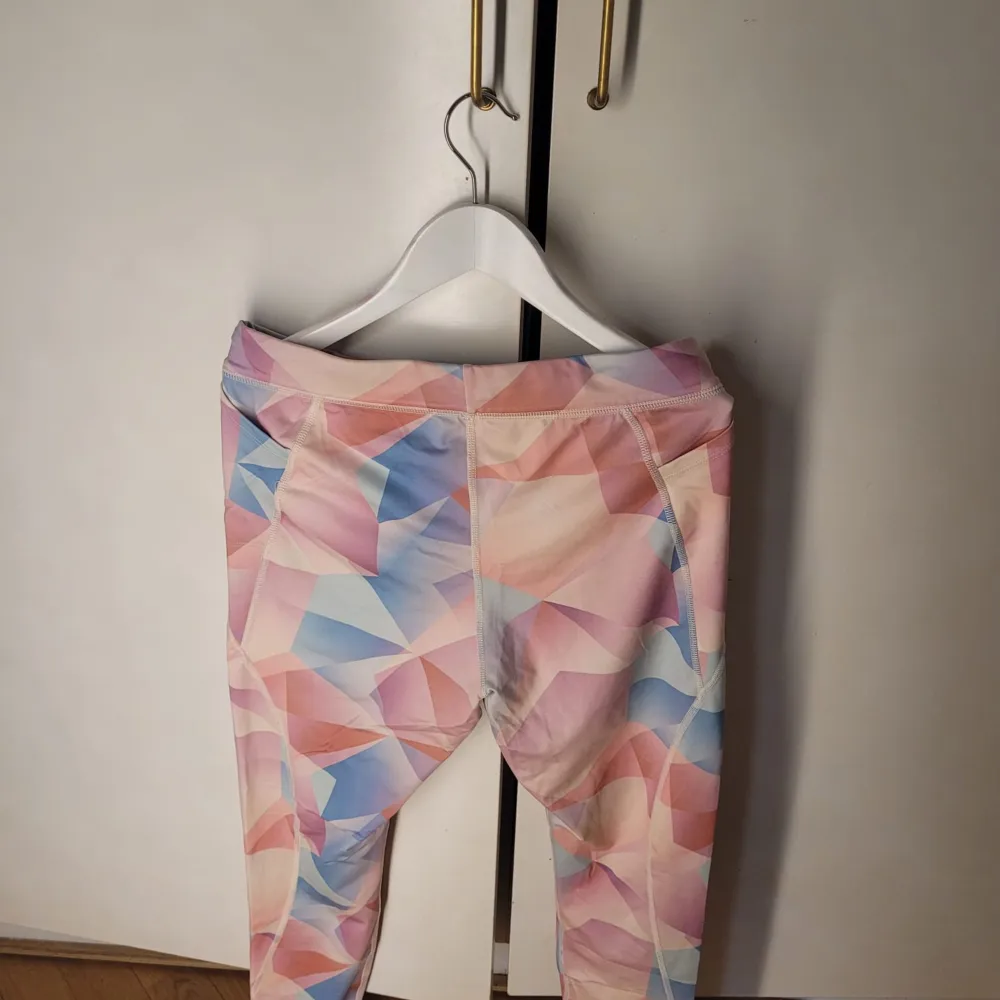 Säljer ett par snygga flerfärgade leggings från Nike i storlek M. De har ett geometriskt mönster i rosa, blått och orange. Perfekta för träning med Dri-FIT material som håller dig torr och bekväm. Midjan är elastisk med Nike-logga för extra stil. Passar perfekt för gymmet eller löprundan!. Farkut & Housut.