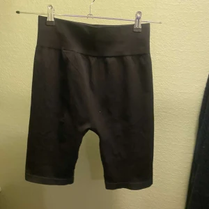 Svarta sportshorts från H&M - Säljer ett par svarta sportiga shorts från H&M i storlek M. Perfekta för träning med en bekväm passform och elastisk midja. De är i nytt skick och redo för ditt nästa träningspass!