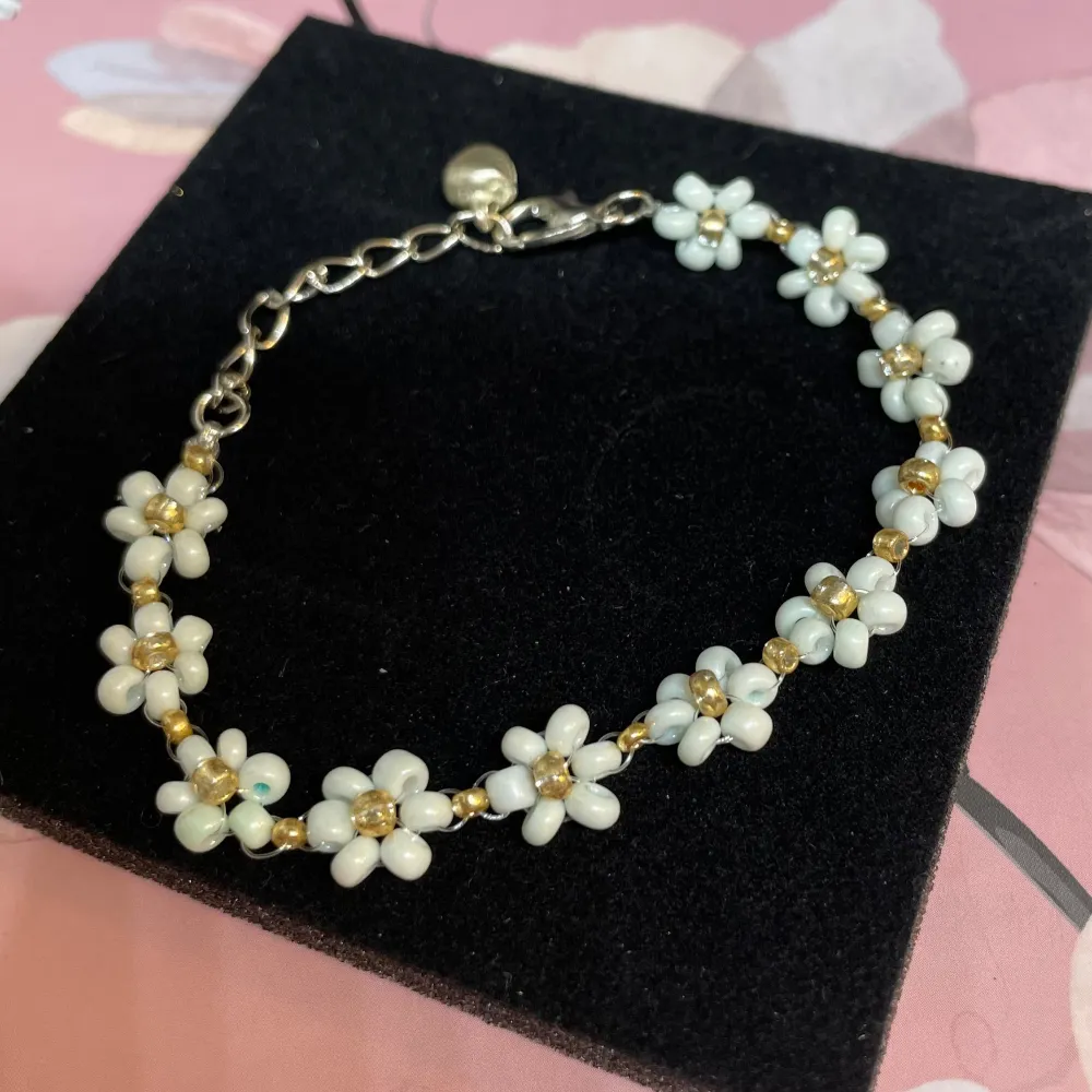 Superfint armband med små blommor i olika färger och pärlor. Perfekt för att ge en somrig touch till din outfit. Armbandet har en justerbar kedja för perfekt passform. Passar både till vardags och festliga tillfällen!. Accessoarer.