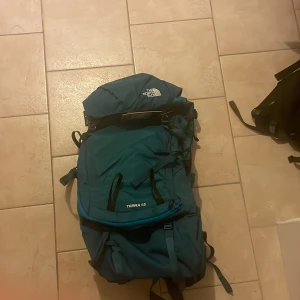 Blå ryggsäck från The North Face - En helt ny north face ryggsäck ordinarie pris 1800 modell Terra 55. Perfekt för vandring och äventyr med gott om utrymme och justerbara remmar för bästa komfort. Den är i mycket bra skick och redo för nya äventyr! 🌲går lätt att få i 60 liter. Fri frakt vid snabb affär! Du sparar 700 kr vid köp av min väska! 