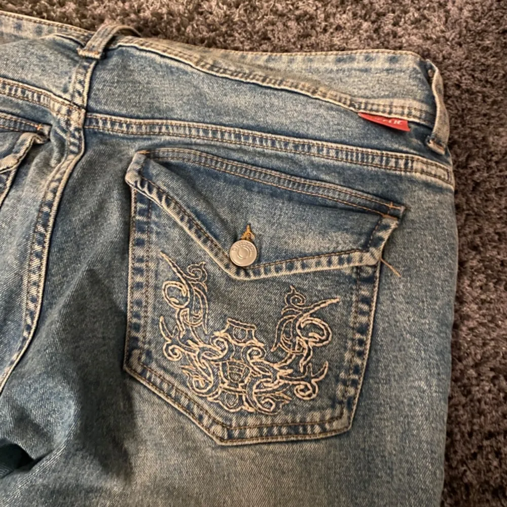 Säljer ett par snygga blå jeans i bra skick. De har en broderad detalj på bakfickan som ger en unik touch. Jeansen är av normal passform och har en klassisk stil. Perfekta för vardagsbruk eller en avslappnad utekväll.. Jeans & Byxor.