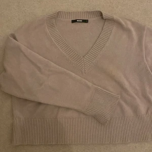 Beige stickad tröja från Bik bok - Mysig beige stickad tröja från bik bok  med v-ringning och ribbade detaljer vid ärmslut och nederkant. Perfekt för kyliga dagar och passar både till vardags och lite finare tillfällen. Superbekväm och stilren!