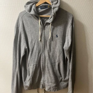 Polo Ralph Lauren - Zip hoodie - Säljer en snygg grå hoodie från Polo Ralph Lauren i storlek L. Den har en dragkedja framtill och en klassisk broderad logga på bröstet. Tröjan är enbart använd tre gånger och säljs eftersom den är för stor för mig. Tröjan är alltså helt i nyskick. Hör av dig vid intresse eller funderingar! 😊