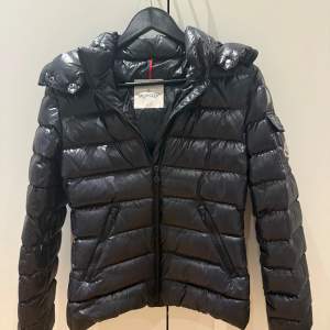 Säljer en snygg svart dunjacka från Moncler i mycket bra skick. Jackan har en quiltad design med dragkedja och en praktisk huva. Perfekt för vintern. Har äkthetsbevis så be om det om du vill ha. Storlek 14år