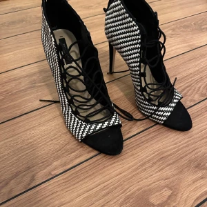 Svartvita klackskor med snörning - Snygga svartvita klackskor från Zara Basic i storlek 41. De har ett coolt rutigt mönster och elegant snörning framtill. Perfekta för en utekväll eller fest! Skorna har en spetsig tå och dragkedja bak för enkel påtagning. Skulle säga att de passar bättre till en storlek 40.
